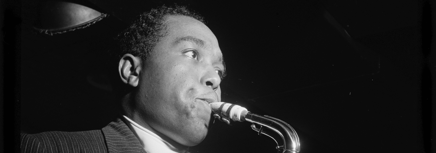 A black-and-white image of Charlie Parker playing the saxophone, capturing the essence of a jazz performance with focus and intensity.