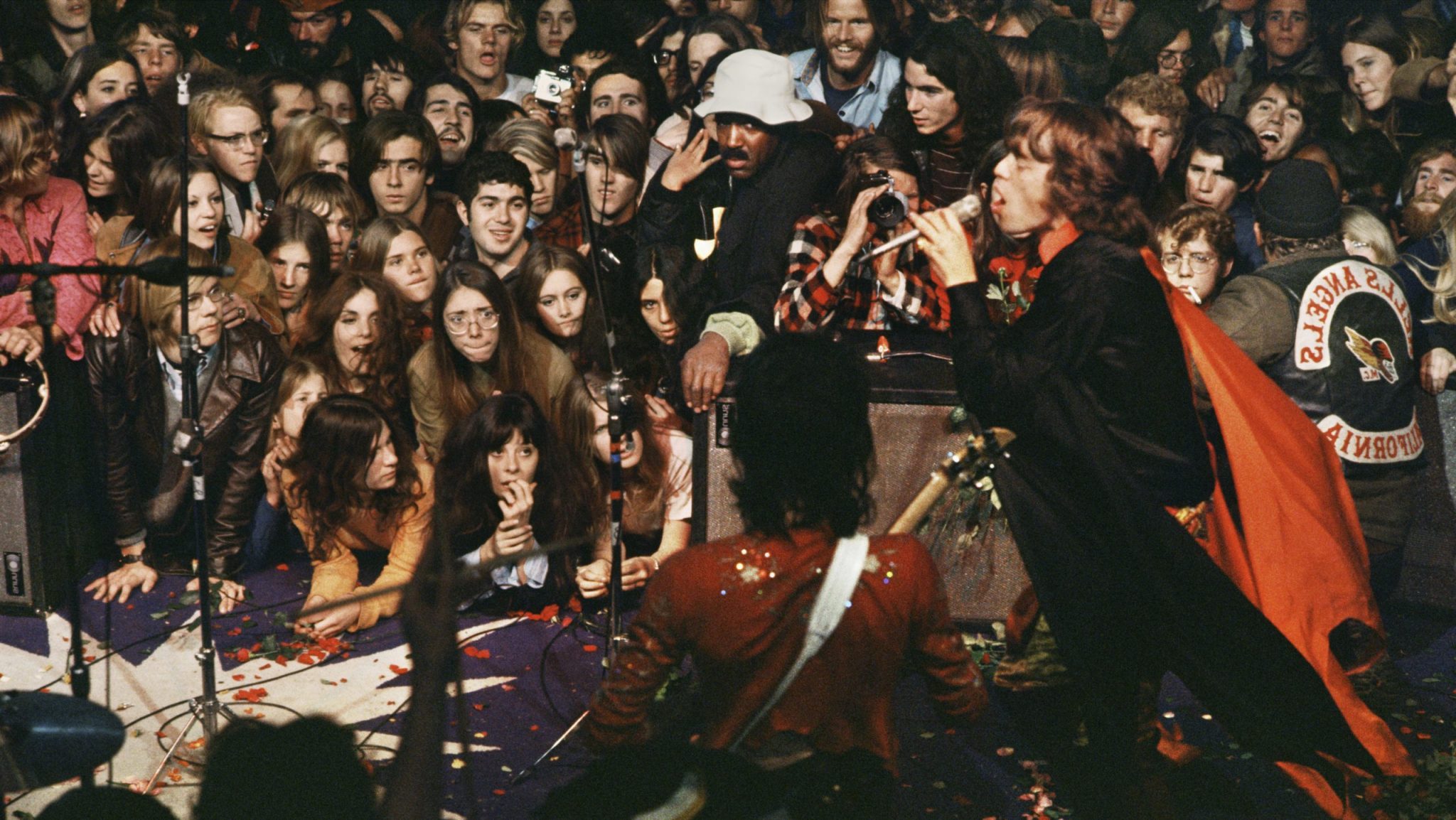 Beatles concert with an enthusiastic crowd watching musicians perform onstage, evoking a sense of 1970s rock and roll nostalgia.
