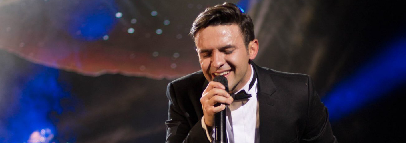A passionate singer delivers a powerful performance onstage, complete with a microphone in hand and a dynamic lighting backdrop.