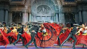 Vibrant folkloric dance performance in front of an ornate building, showcasing traditional costumes and dynamic movement.