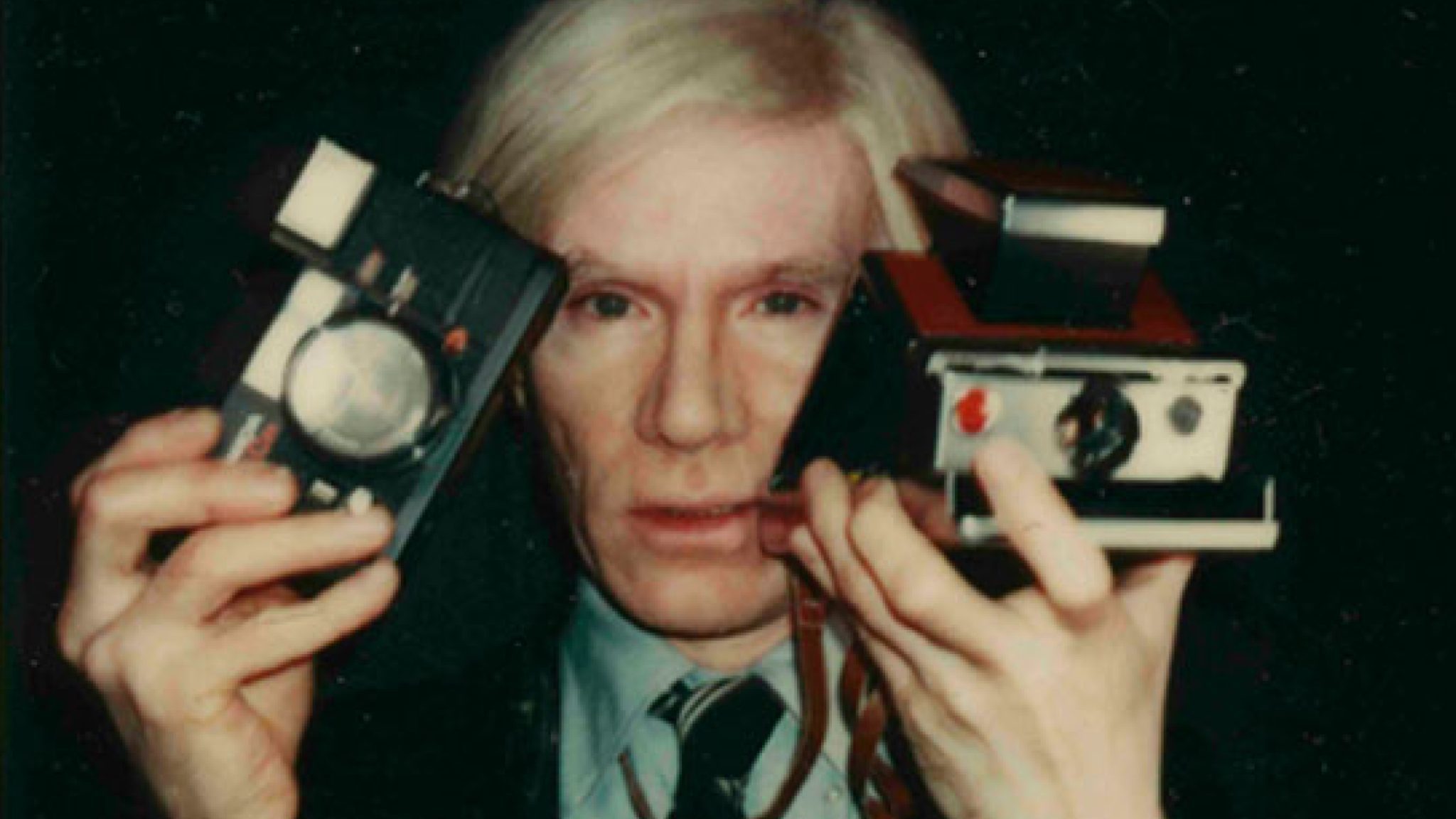 Vintage flair: an individual showcasing classic polaroid cameras, framed by the nostalgic magic of instant photography.