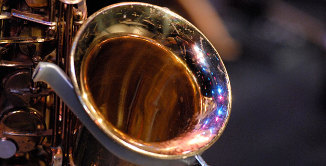 Golden saxophone bell shines under stage lights during a jazz performance.