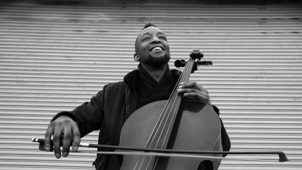 A joyful cellist plays with passion against an urban backdrop, the smile on his face reflecting the soulful music he creates.