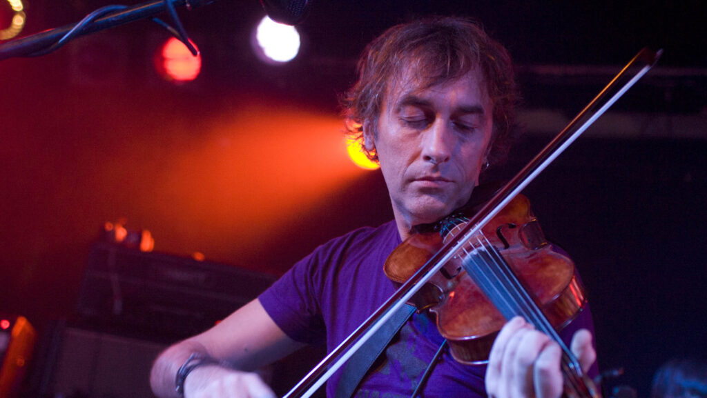 A passionate violinist immersed in his performance on stage under vibrant stage lighting.