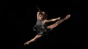 Grace in motion: a dynamic dance leap captured in the silence of the dark.