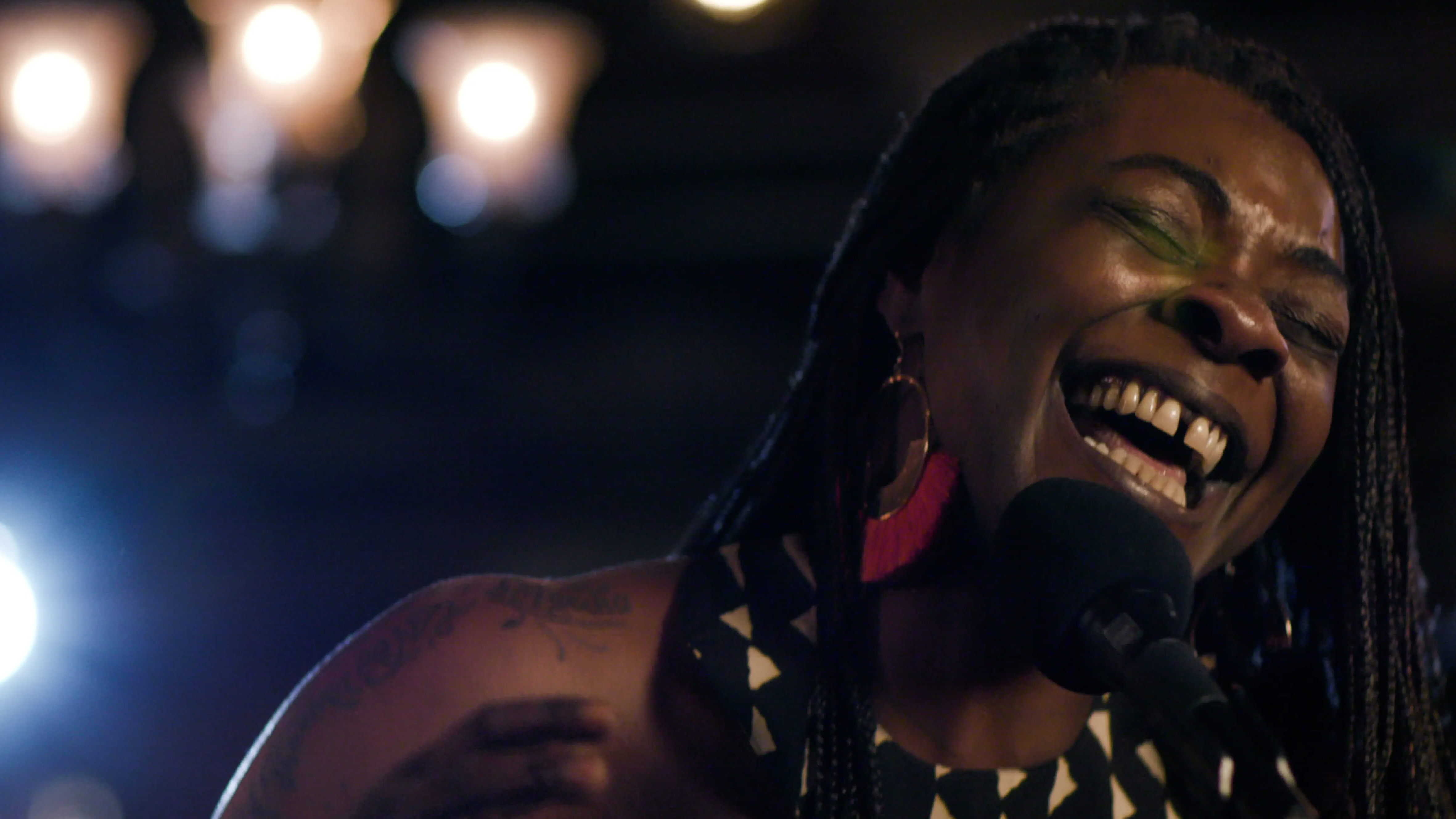 A soulful Buika passionately performing with a joyful expression under warm stage lighting.