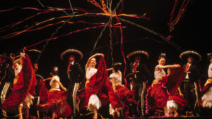 Colorful folkloric dance performance celebrating traditional mexican culture with dancers in vibrant costumes and sombreros under a shower of celebratory streamers.