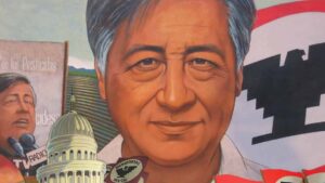 A mural with a prominent portrait of a man, featuring activists, political symbols, and iconic buildings, reflecting a theme of social and political advocacy.