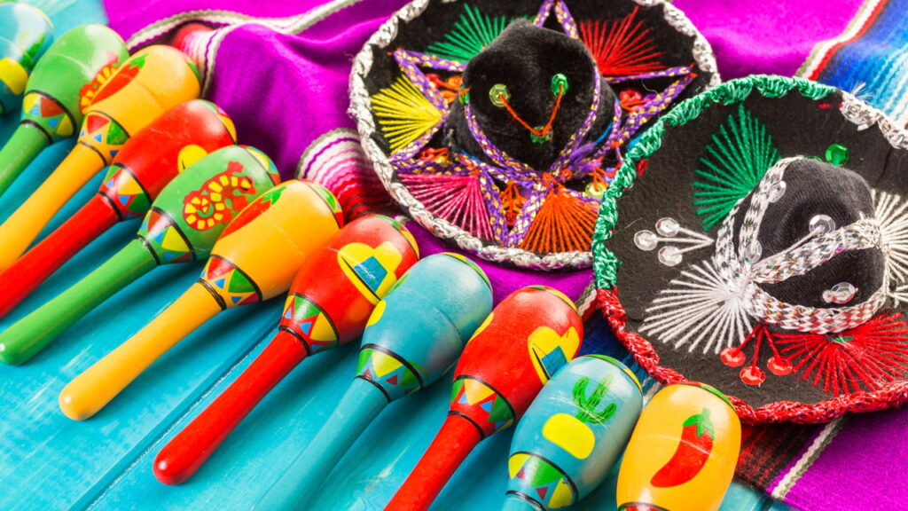 A vibrant display of mexican culture featuring colorful maracas and a traditional sombrero on a wooden background.