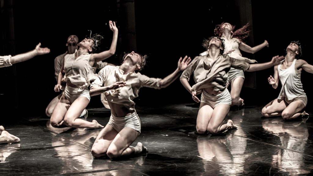 A group of contemporary dancers expressing emotion through movement on stage, their bodies caught in a moment of passionate performance.