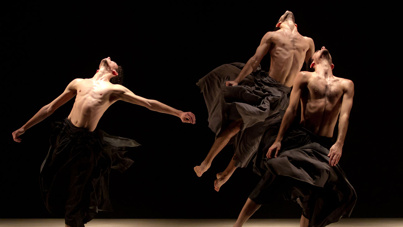 Two dancers in motion, showcasing a dramatic and synchronized leap on stage, embodying both grace and physical strength.
