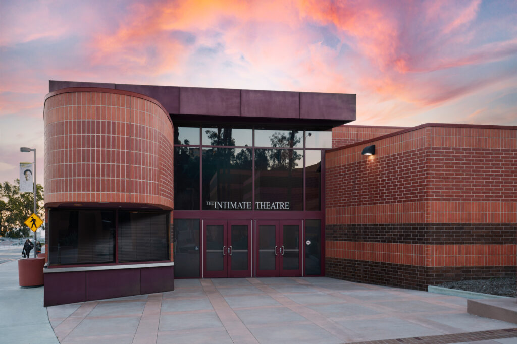 The Intimate Theater entrance adorned with brickwork under a dramatic sunset sky.