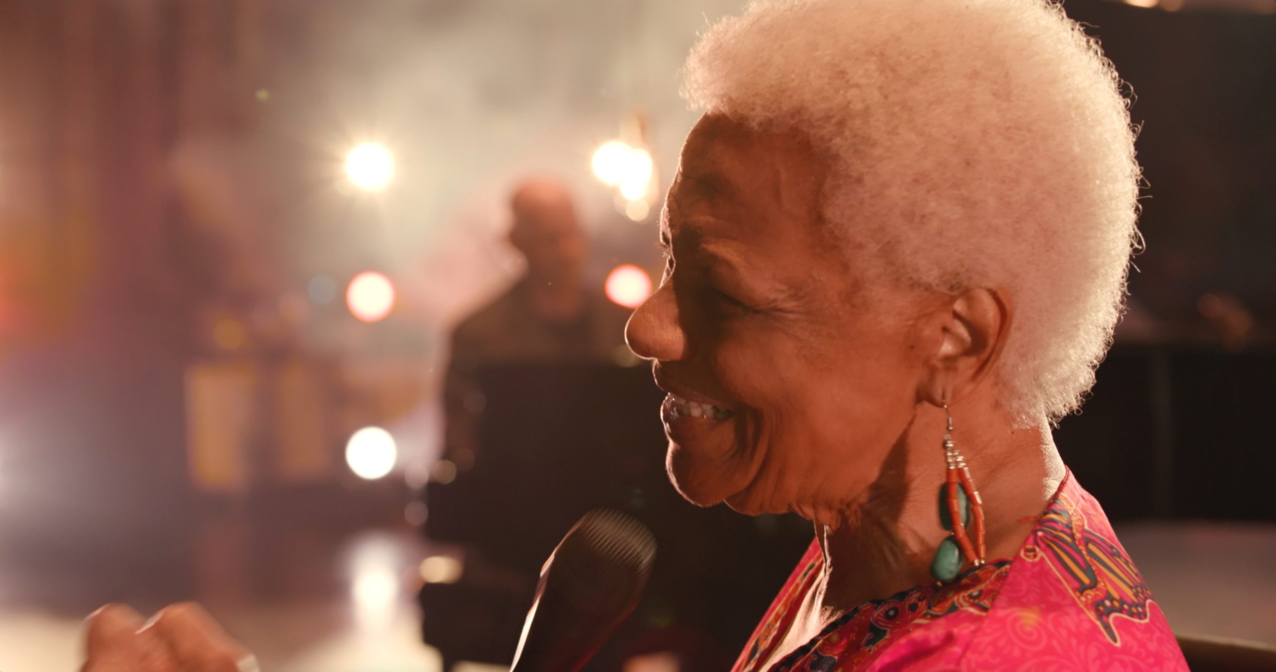 Barbara Morrison with a radiant smile performing on stage, basking in the warm glow of stage lights and a joyful atmosphere.