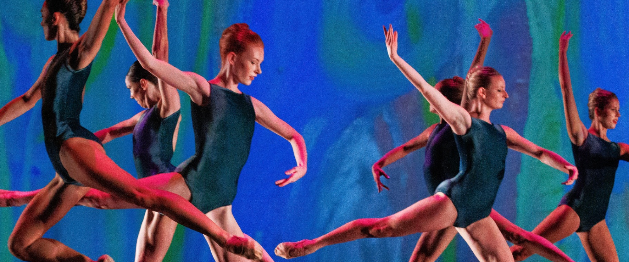 Ballet dancers in dark leotards perform leaps on stage.