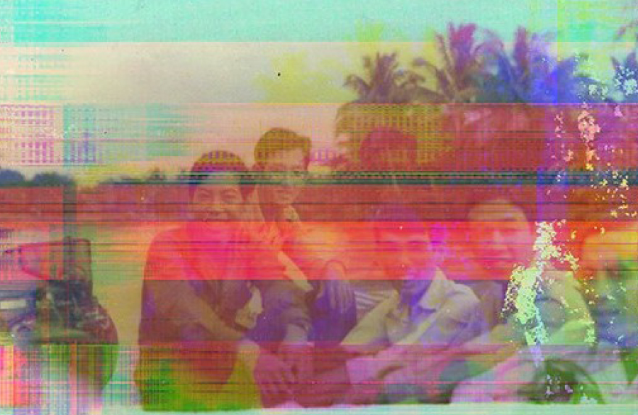 A group of five people sit together outdoors in front of palm trees. The image is distorted with colorful horizontal digital glitches.