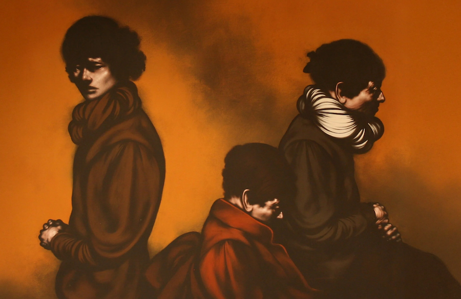 Three figures with dark clothing and scarves are seated against a warm brown background, each looking in different directions with serious expressions.
