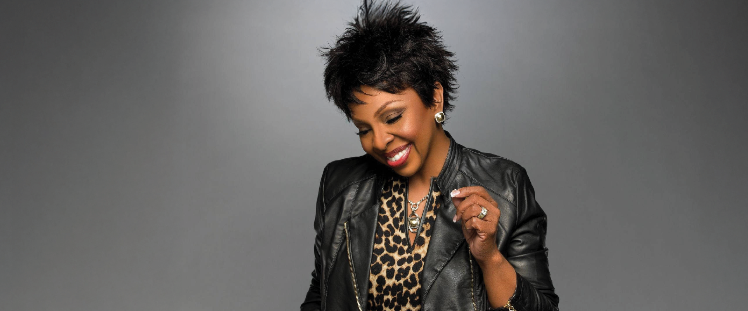 Gladys Knight smiling in black jacket and leopard print shirt.