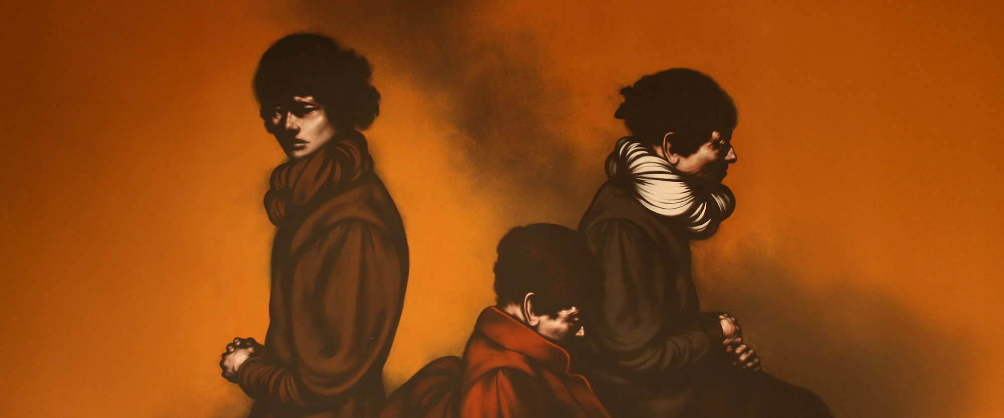 Three people in dark clothing sit and stand against an orange background, each facing a different direction with somber expressions.