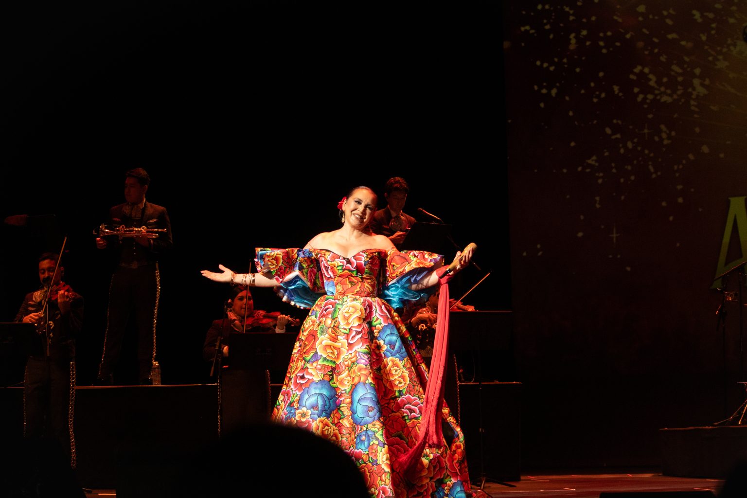 Aida Cuevas in a colorful dress on a stage.