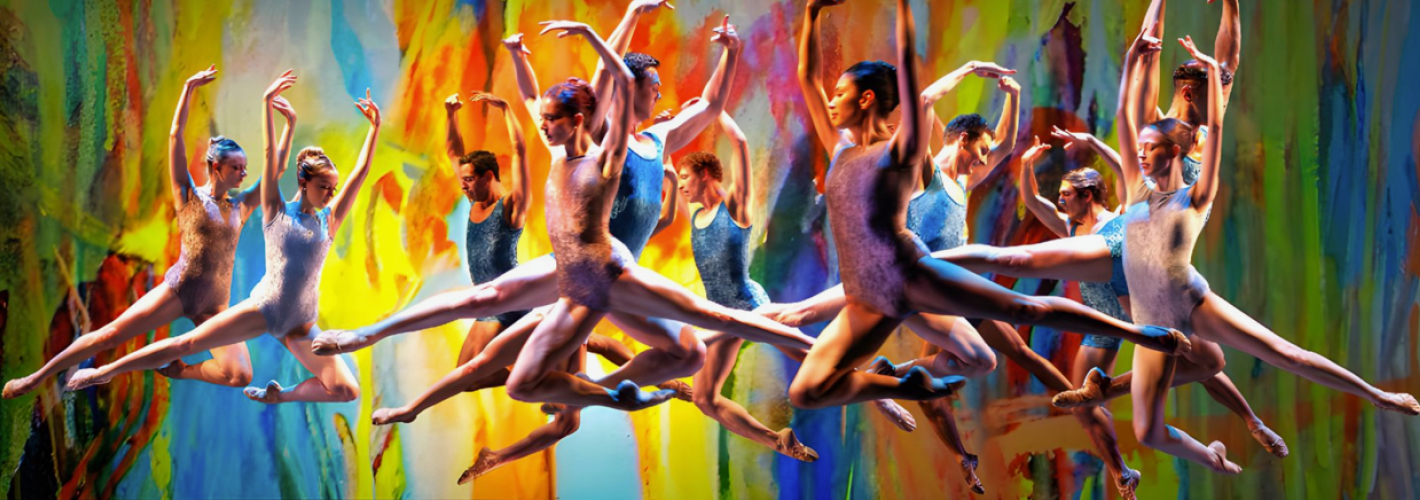 The dancers, a mix of men and women, are suspended in the air in powerful grand jeté split leaps across the stage.