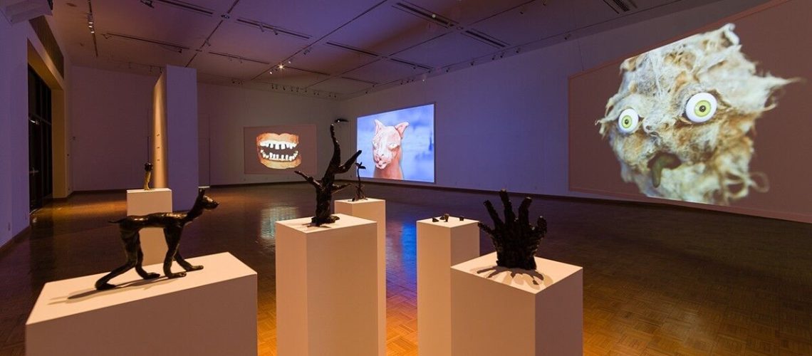 An eclectic modern art gallery showcasing sculptures and whimsical animal-themed projections.